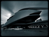 a black and white photo of a building with a cloudy sky